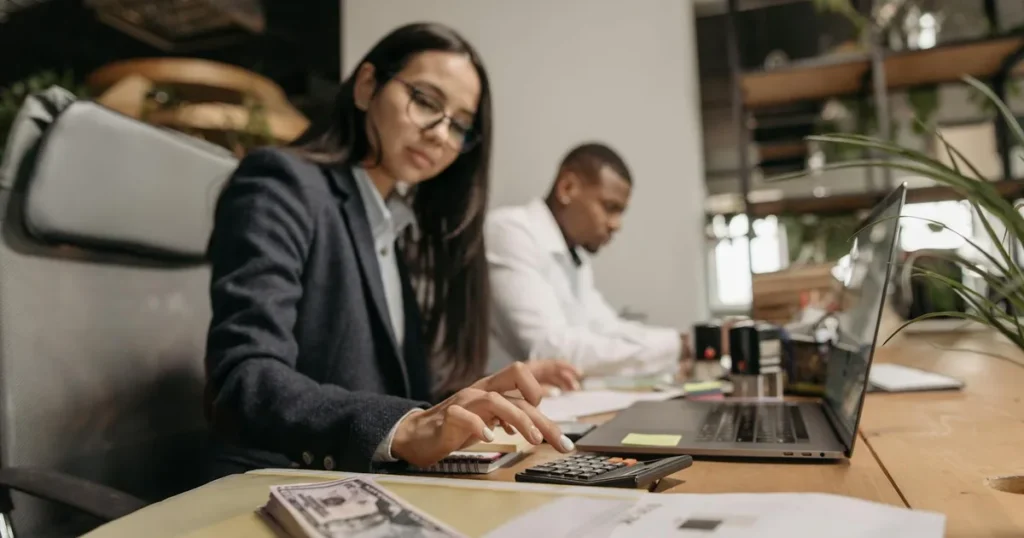 Twee professionals werken samen aan boekhouding op laptop — Exact Online review voor ZZP'ers