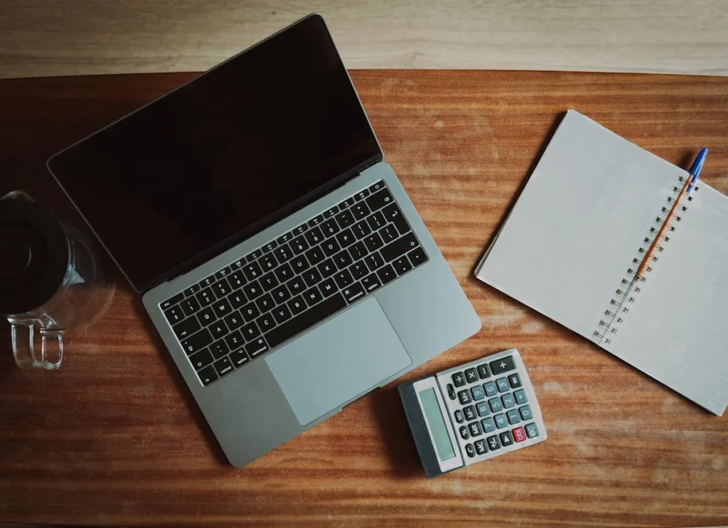 Laptop met rekenmachine en notitieblok op bureau